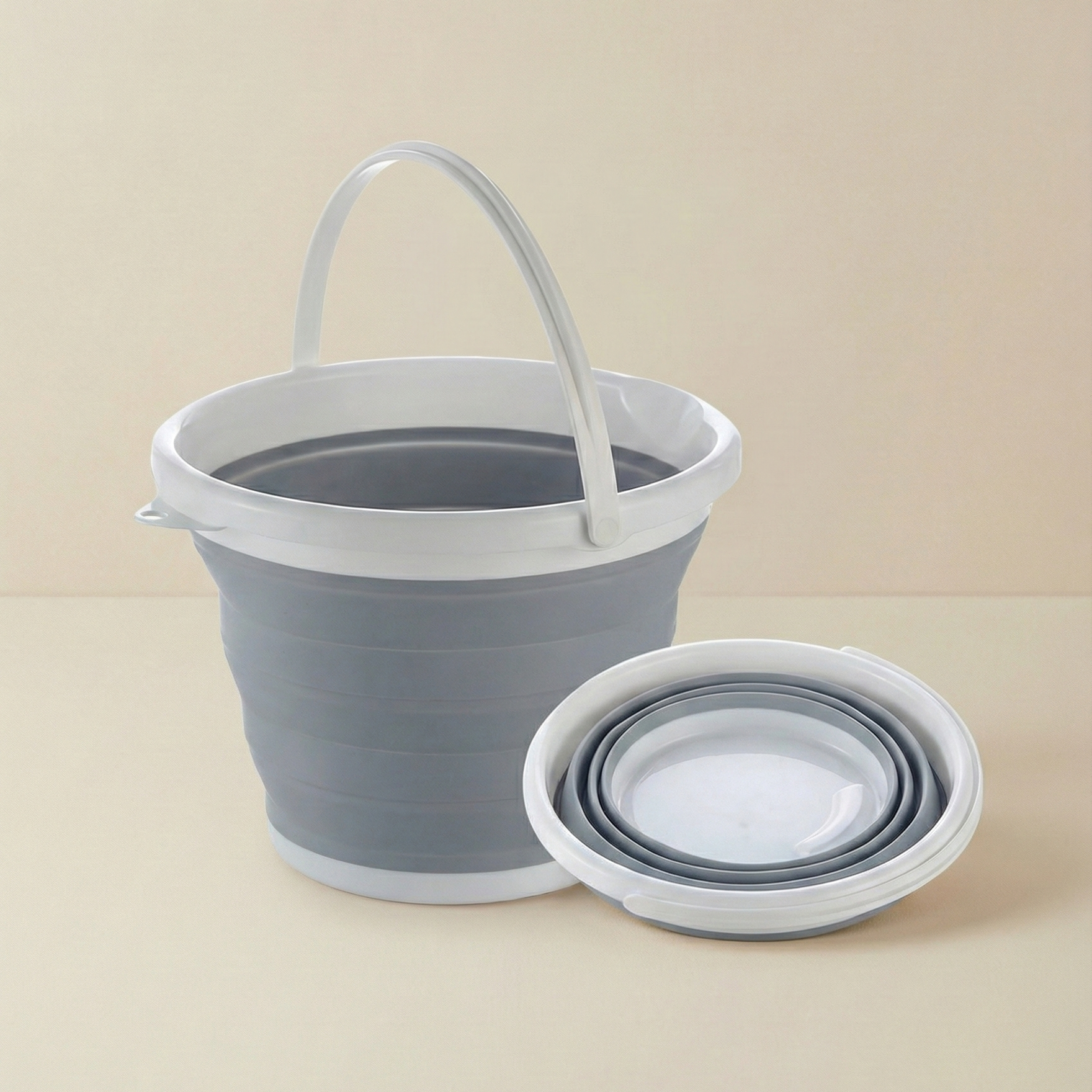 Collapsible gray bucket with handle on a beige background