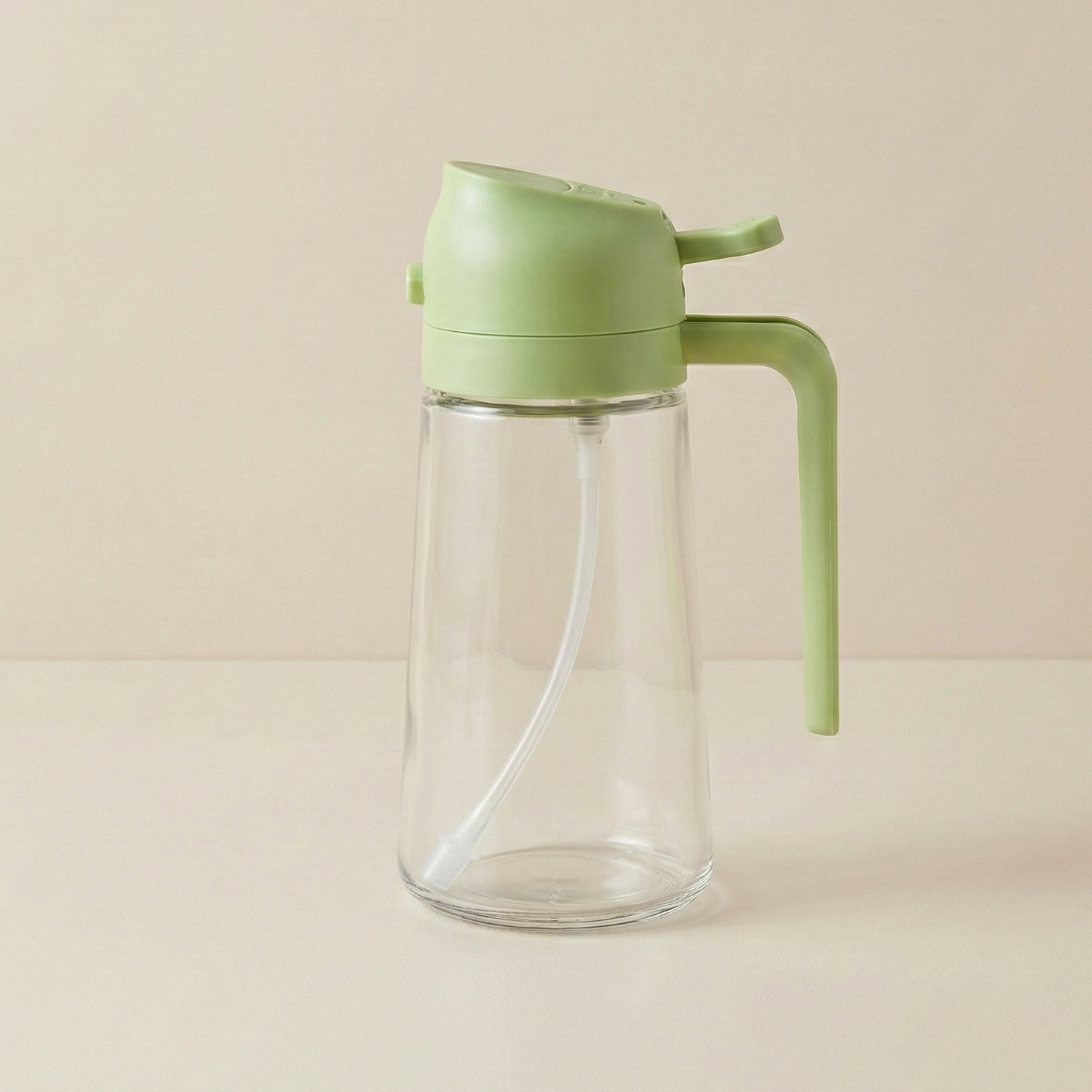 Clear glass bottle with a green lid and handle on a beige background